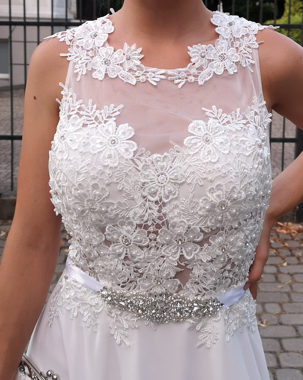 Biała suknia ślubna zdobiona kwiatami koronkowymi i perełkami 